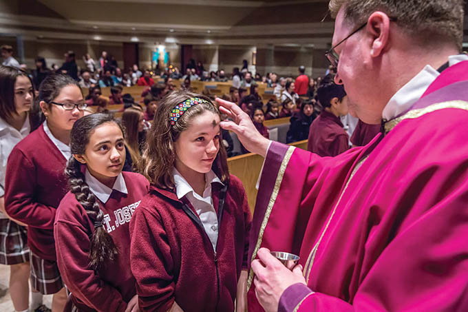 Father Timothy J. Heines, pastor at St. Joseph Catholic Church in Richardson, distributes ashes to St. Joseph Catholic School students during Mass on Ash Wedenesday. (RON HEFLIN/Special Contributor)