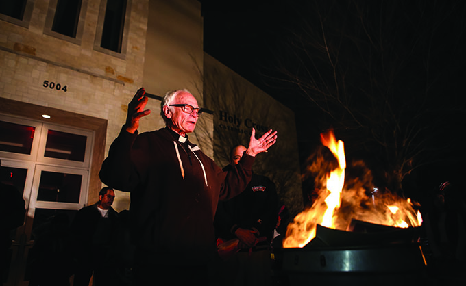 Father Timothy Gollob, pastor of Holy Cross Catholic Church, leads a prayer on Feb. 17 as he burns representative documents from a loan paid off by the church in celebration of retiring a construction debt. About 200 parishioners gathered at the church on Feb. 17 for a Mardi Gras celebration that included food, dancing and the burning of dried palms, individual intentions and a mortgage note signifying that the parish had paid off a 15-year $400,000 note in three years to completely pay off its $5 million sanctuary that was dedicated in 2011. 