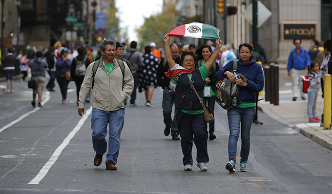 A woman displays the flag of Mexico on her way with others to the Festival of Families with Pope Francis in Philadelphia Sept. 26. The Mexican bishops' conference and the Vatican have confirmed Pope Francis will visit Mexico in 2016. (CNS photo/Bob Roller) 