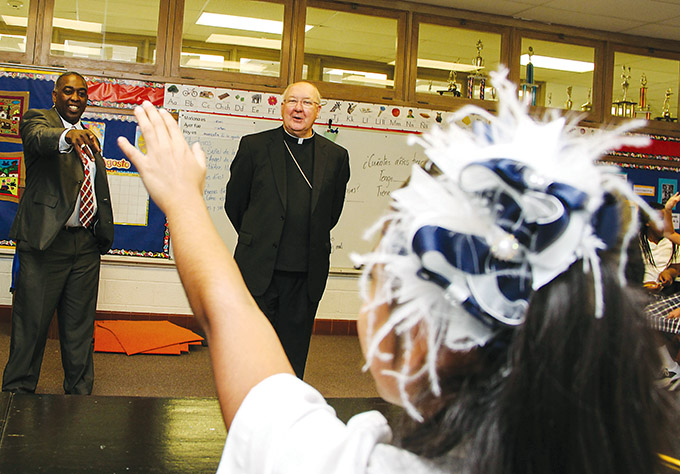 With the help of Principal Chris Sanders (left), Bishop Kevin J. Farrell answers questions from St. Pius X Catholic School students during a visit to the campus in September 2015.