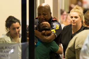A Dallas police officer is comforted July 7 at Baylor University Hospital's emergency room entrance after a shooting attack. Snipers shot and killed five police officers and wounded seven more at a demonstration in Dallas to protest the police killing of black men in Baton Rouge, La., and a suburb of St. Paul, Minn. Two civilians also were injured in Dallas. (CNS photo/Ting Shen, The Dallas Morning News handout via Reuters)