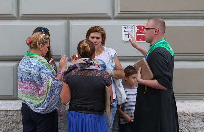 A priest prays over pilgrims along a street July 24 in Krakow, Poland, ahead of World Youth Day. (CNS photo/Bob Roller)