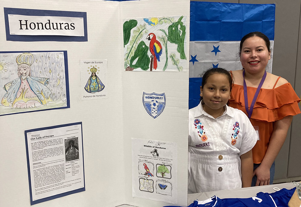 Altair Magaña, alumna de cuarto grado posa junto a su mamá, Ingrid Cruz, junto a la mesa dedicada a la cultura hondureña, el 9 de febrero en el gimnasio de la Academia SPSA. 